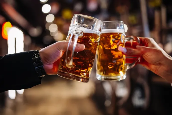 Two people clinking beer glasses together, ready to enjoy it in moderation